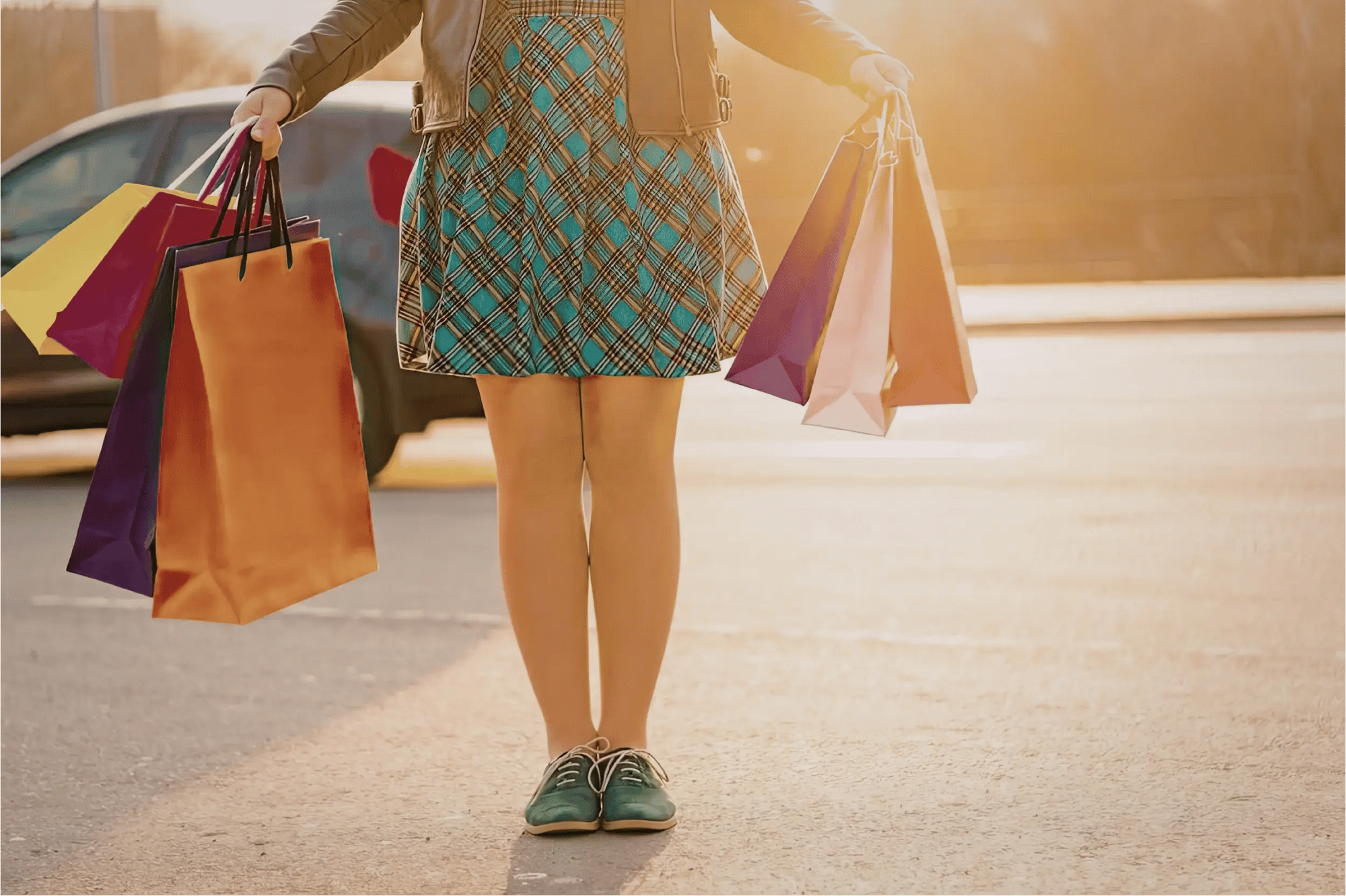 je ziet benen en romp van een vrouw met aan beide handen winkeltassen