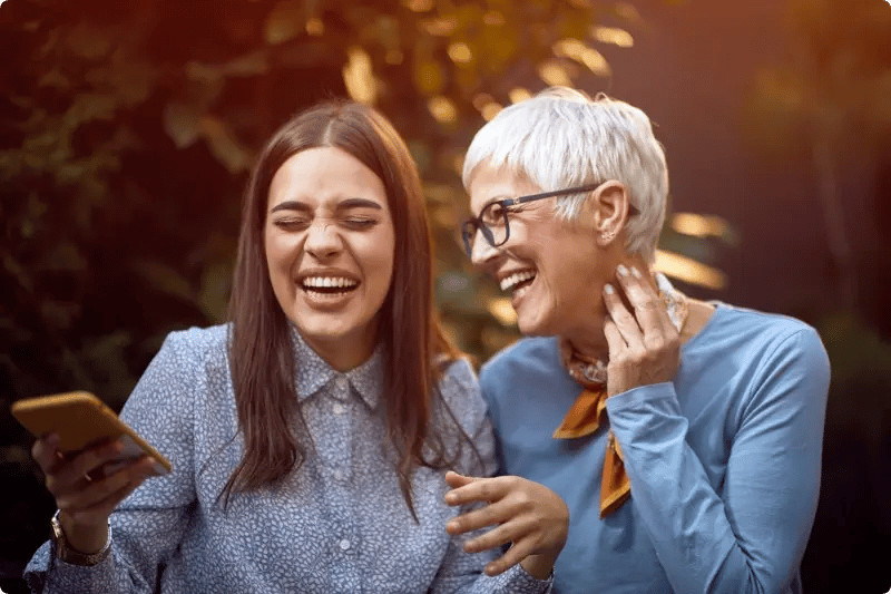 Vrouw en dochter lachend met telefoon in handen