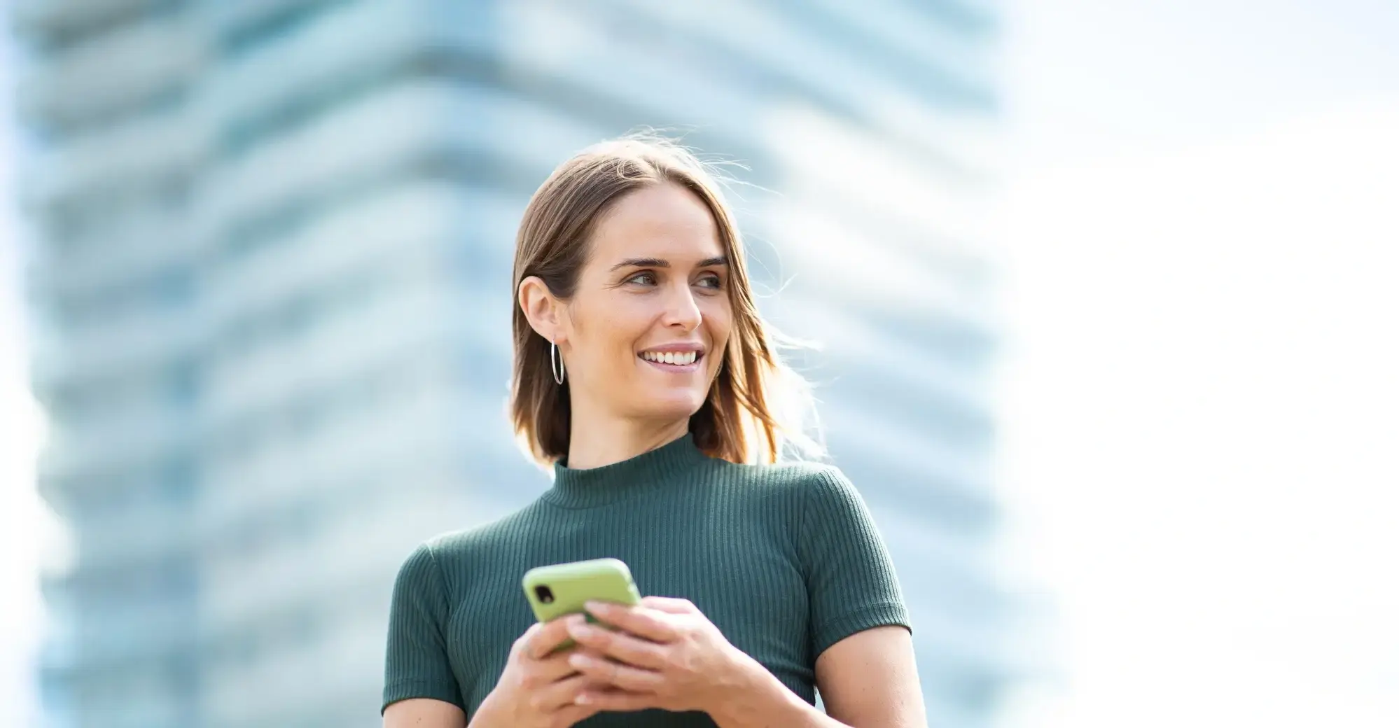 Vrouw kijkt blij weg van telefoon 