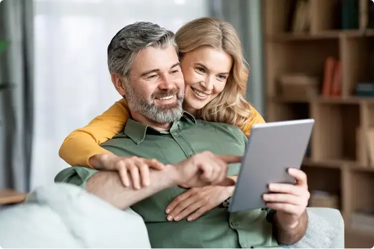 Stel kijkt blij naar een webinar over het instapmoment bij beleggen