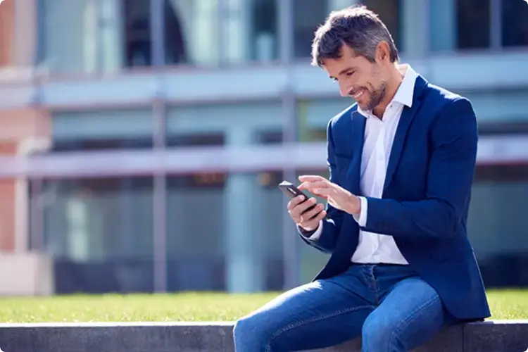 Man kijkt blij naar zijn telefoon omdat hij belegt met geld dat hij langere tijd kan missen