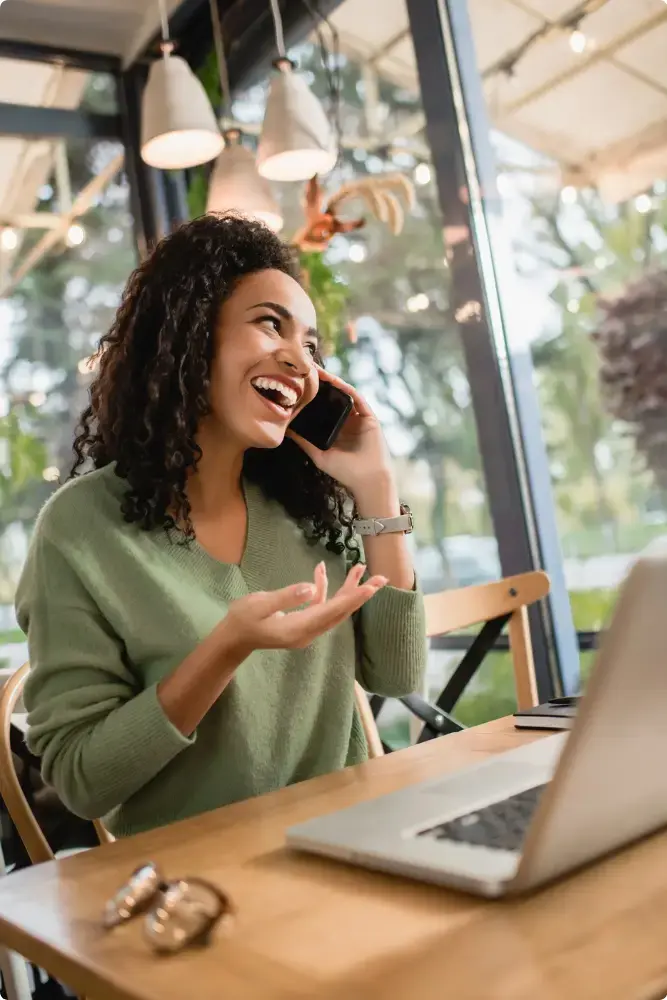 Vrouw aan de telefoon lachend naar laptop