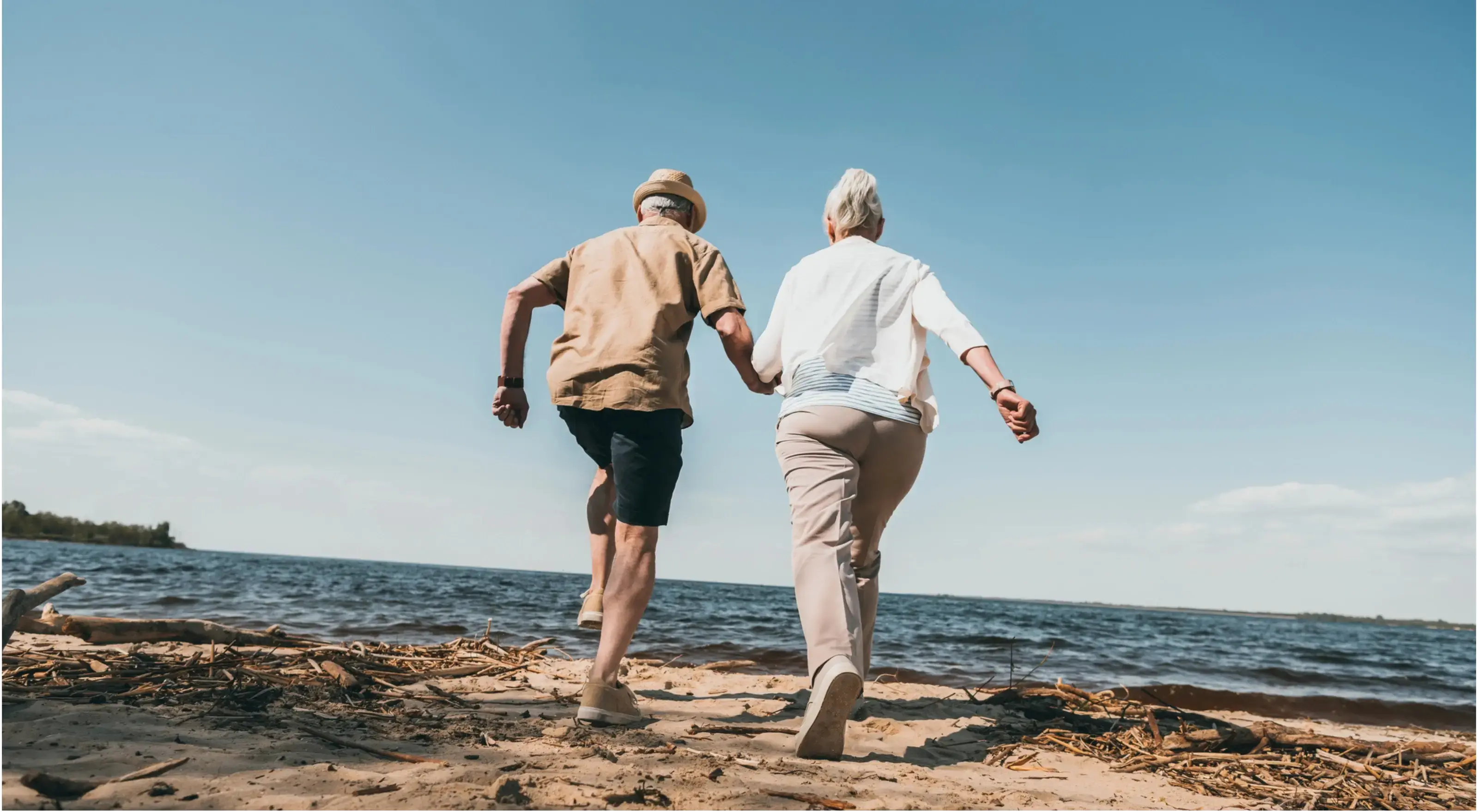 Twee mensen met pensioen die hand in hand rennen over het strand