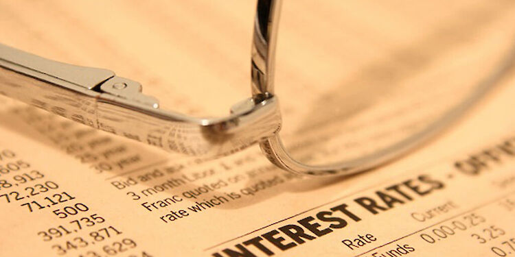 close up van een bril op een papier met cijfers en interest rates