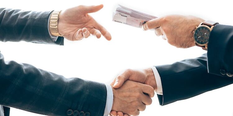 Close-up van mannen die elkaar de hand schudden terwijl ze met hun andere hand geld overgeven.