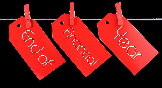 drie rode kaartjes met de woorden 'end of', 'financial', 'year' aan een waslijn met rode knijpers