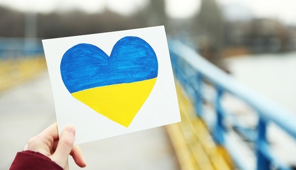 hand met briefje met een hart in de kleuren van Oekraine erop